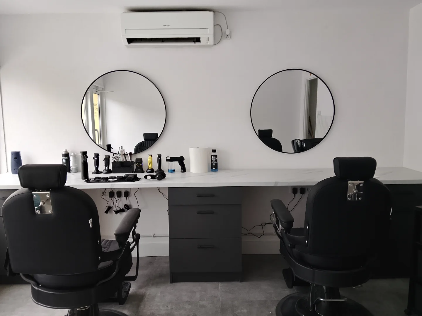 Wnętrze OSTCUT Barbershop — czyste stanowiska i okrągłe lustra